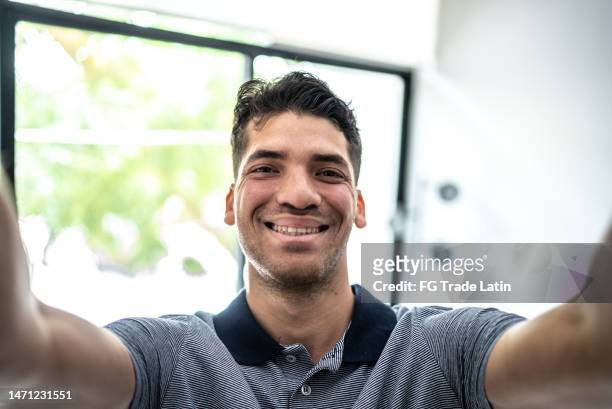 porträt eines jungen mannes, der zu hause ein selfie macht - kameraperspektive - blick durch kameraobjektiv stock-fotos und bilder