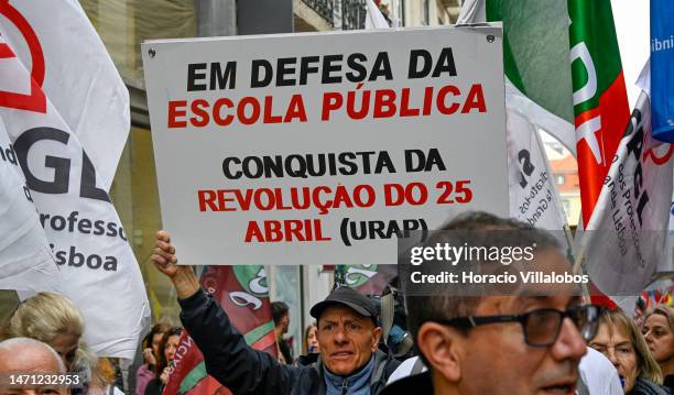 Teachers hold signs while marching in protest from Rossio Square for better working conditions to the Portuguese Parliament during a strike called by...