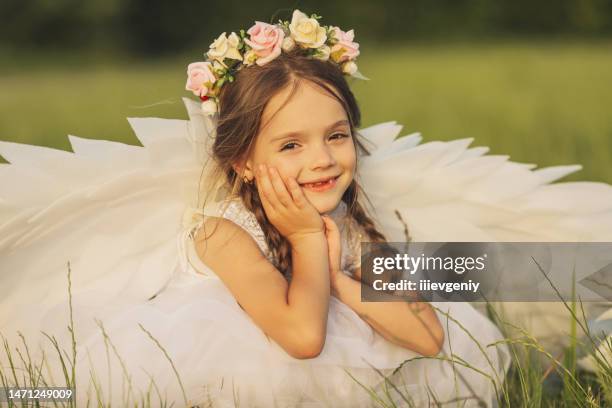 ángel con alas blancas sobre hierba verde. chica rubia vestida sobre fondo de verano - comunion fotografías e imágenes de stock