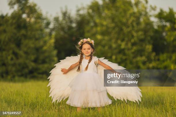 angel with white wings on green grass. blonde girl in dress on summer background - angel white dress stock pictures, royalty-free photos & images