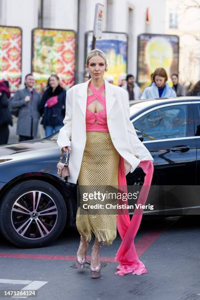Leonie Hanne wears pink cut out top, beige net skirt with fringes, white blazer, Valentino bag, platform sandals outside Giambattista Valli during...