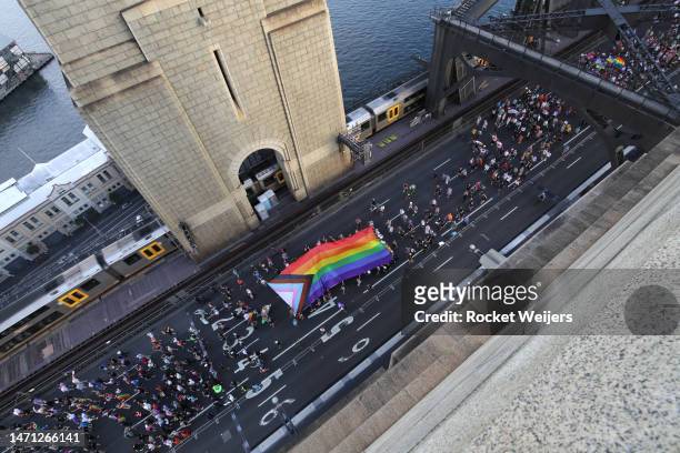 The Progress Pride flag is carried over the Sydney Harbour Bridge as people take part in Pride March on March 05, 2023 in Sydney, Australia. 50,000...