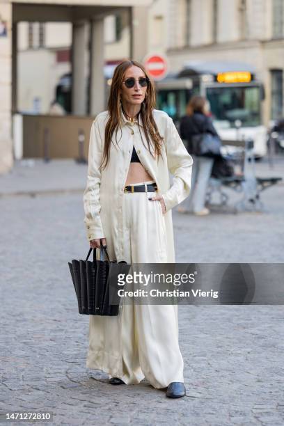 Chloe Harrouche wears black bag, beige wide leg pants, button shirt outside Victoria Beckham during the Paris Fashion Week - Womenswear Fall Winter...