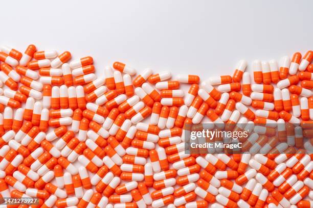 abundance of orange colored capsule pills - kapsel stock-fotos und bilder