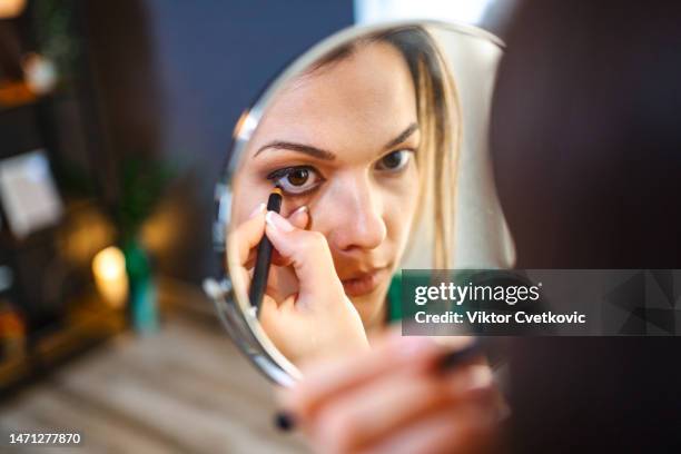 hermosa mujer aplicando delineador de ojos kajal en sus ojos - kajal fotografías e imágenes de stock