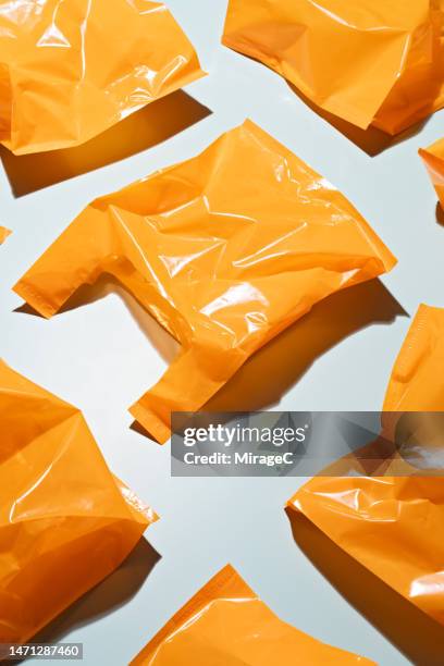 orange colored plastic bags on blue background - sac en plastique photos et images de collection