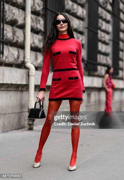 Guest is seen wearing a red and black dress, red stockings, cream heels, black The Attico bag and black sunglasses outside the Hermes show during...