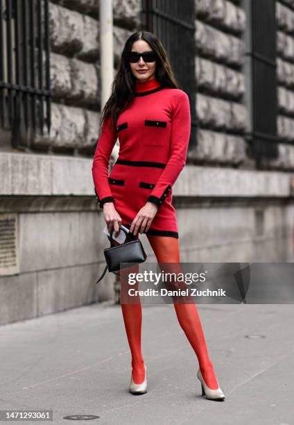 Guest is seen wearing a red and black dress, red stockings, cream heels, black The Attico bag and black sunglasses outside the Hermes show during...