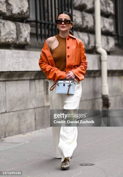 Alexandra Pereira is seen wearing an orange Hermes jacket, orange top, white pants and light blue and brown Hermes bag outside the Hermes show during...