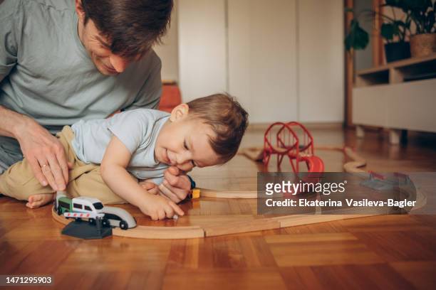 dad and son play wooden trains at home - model train stock pictures, royalty-free photos & images