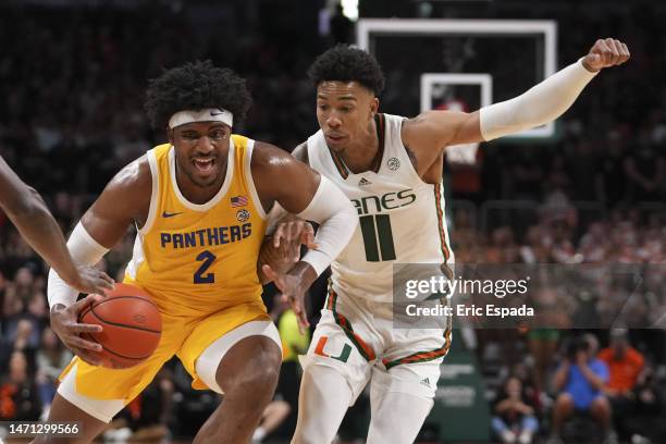 Blake Hinson of the Pittsburgh Panthers drives to the basket while being defended by Jordan Miller of the Miami Hurricanes during the first half at...