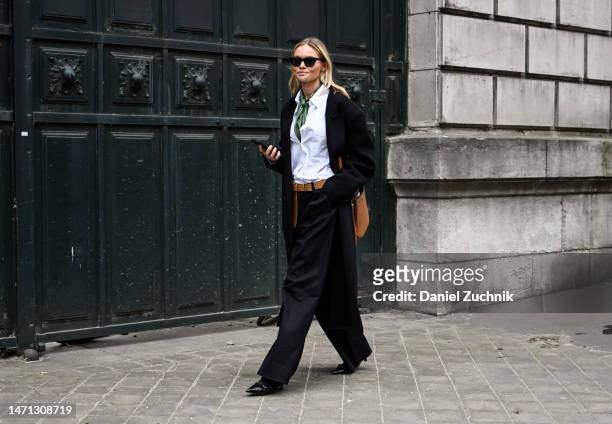 Claire Rose is seen wearing a black jacket, white shirt, black pants, brown bag and green scarf outside the Hermes show during Paris Fashion Week F/W...