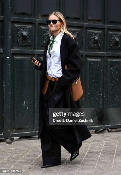 Claire Rose is seen wearing a black jacket, white shirt, black pants, brown bag and green scarf outside the Hermes show during Paris Fashion Week F/W...