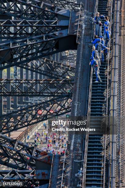 Bridge climbers stand watching as people take part in the Pride March across the Sydney Harbour Bridge on March 05, 2023 in Sydney, Australia. 50,000...