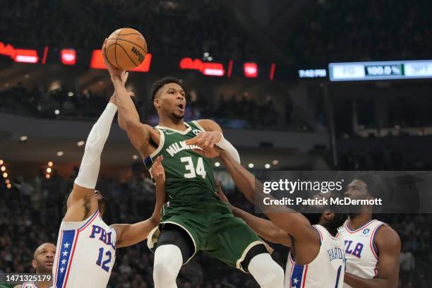 Giannis Antetokounmpo of the Milwaukee Bucks passes the ball against Tobias Harris and James Harden of the Philadelphia 76ers in the first half of...