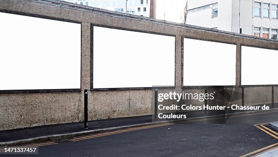 Four white and empty advertising panels on a weathered wall with sidewalk and street in London, England, United Kingdom Four white and empty advertising panels on a weathered wall with sidewalk and street in London, England, United Kingdom