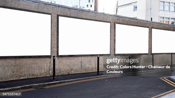 four white and empty advertising panels on a weathered wall with sidewalk and street in london, england, united kingdom - big city bildbanksfoton och bilder