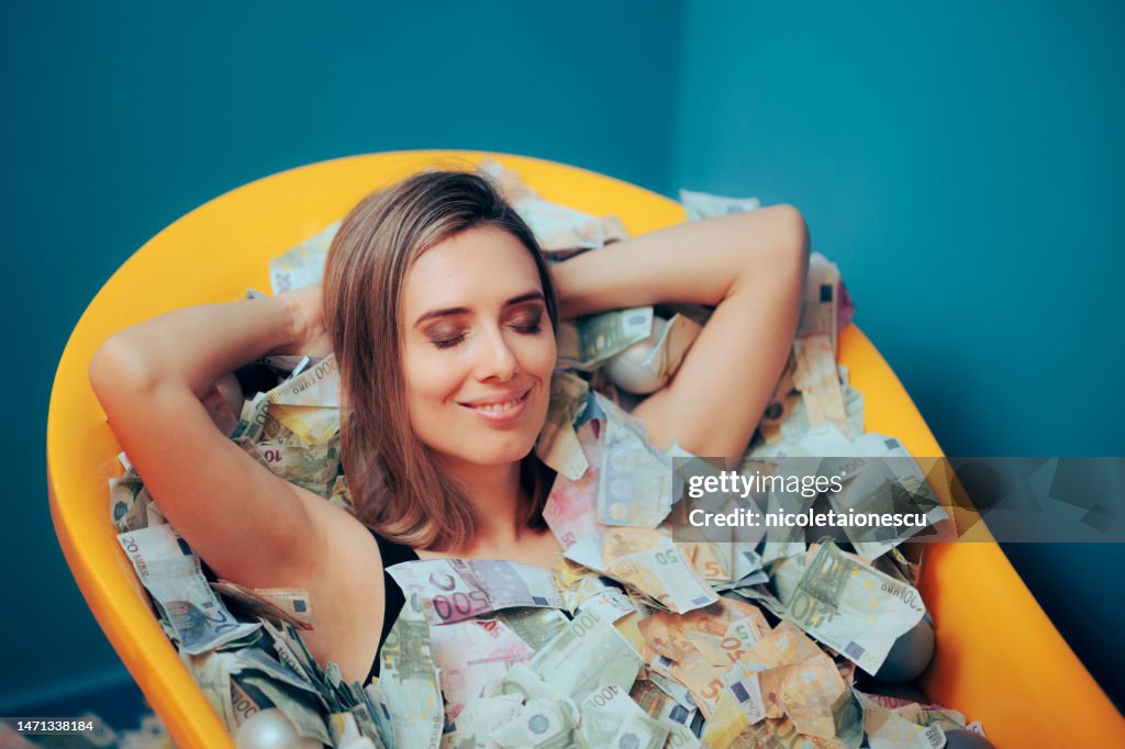 Mujer rica y despreocupada bañándose en una tina de dinero