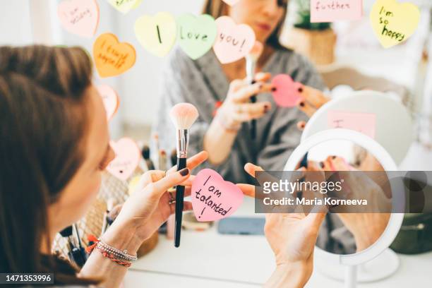 woman stick a sticker with affirmations on the mirror. - health motivational quotes stock pictures, royalty-free photos & images