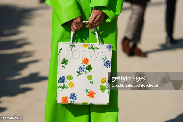 Guest wears a neon green shiny leather jacket, matching neon green large pants, a white shiny leather with blue and yellow flower print pattern...