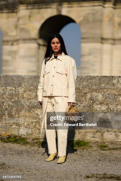 Guest wears a black t-shirt, a beige cargo denim jacket, beige cargo denim matching large pants, a brown shiny leather checkered belted handbag,...