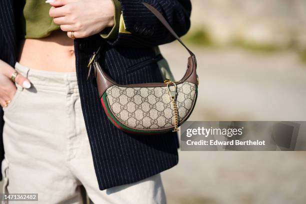 Guest wears a khaki with embroidered white print pattern cropped sweater from Balmain, a black striped print pattern blazer jacket, beige cargo...