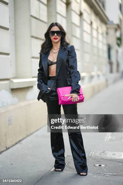 Guest wears black futurist sunglasses, gold necklaces, a black blazer jacket, a black lace print pattern bra underwear, black silk high waist suit...