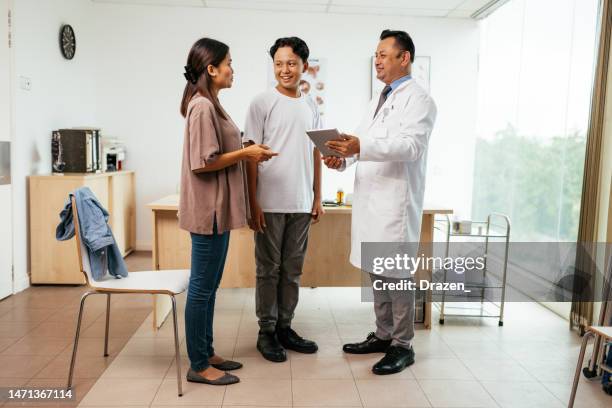 asian family with teenage boy visiting general practitioner. doctor using digital tablet to follow the patient's diagnosis - doctor stethoscope patient whole body stock pictures, royalty-free photos & images