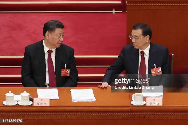 Chinese President Xi Jinping talks with Premier Li Keqiang during the opening of the first session of the 14th National People's Congress at The...