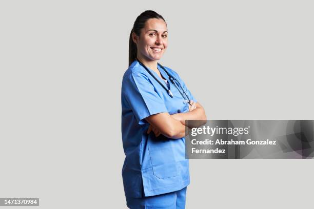 a nurse standing with her arms crossed looking at the camera smiling in a studio shot - nurse and portrait and white background and smiling and female and looking at camera stock pictures, royalty-free photos & images