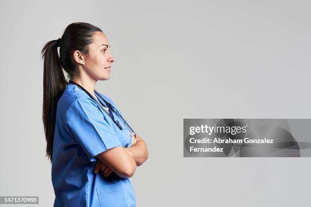 side view of a nurse wearing a blue scrub looking forward to a copy space in a studio shot - female doctor on white stock pictures, royalty-free photos & images