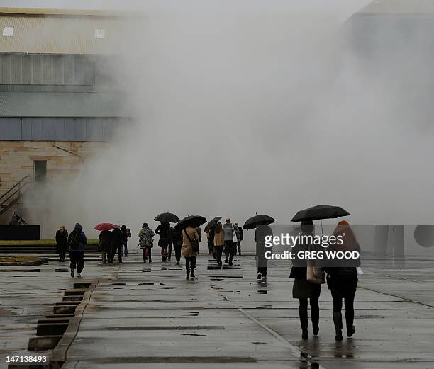 Members of the media walk towards wet artificial fog, part of an installation by Japanese artist Fujiko Nakaya, on Cockatoo Island near Sydney during...