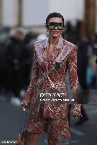 Lisa Rinna wears huge brown/green sunglasses, a varnished blazer jacket with floral print in red, matching shorts, a metallic bag, outside Paco...