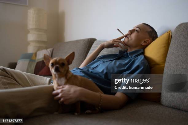 relaxed woman smoking weed at home - cigarette bud stock pictures, royalty-free photos & images
