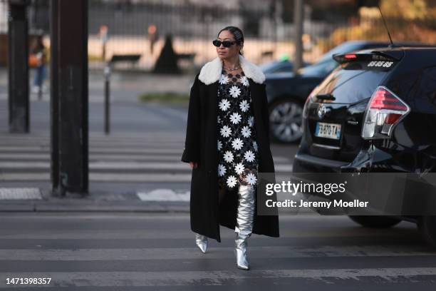 Miki Cheung wears Prada black sunglasses, silver hair clips, a black long coat with white fake fur, a black/white flowered dress, a metallic bag and...