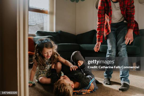 young siblings playfully wrestle in a domestic environment - female wrestling stock pictures, royalty-free photos & images