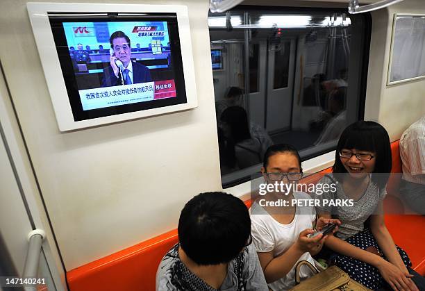 Television screen on a subway train in Shanghai shows Chinese President Hu Jintao speaking by telephone to the three Chinese astronauts aboard the...