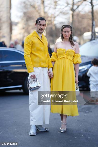 Guest wears a white latte turtleneck pullover, a yellow embossed flower pattern jacket, white denim suit pants, a silver shiny varnished leather...