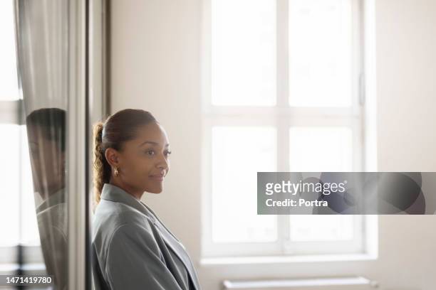 thoughtful young african businesswoman standing in office - diretor geral imagens e fotografias de stock