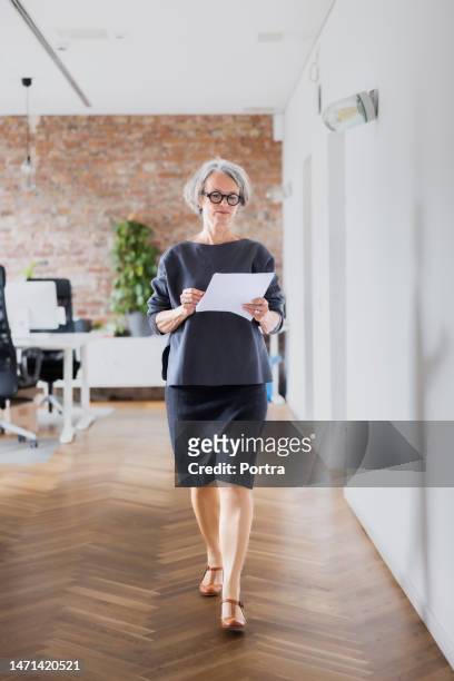 senior businesswoman walking in office corridor - managing director office stock pictures, royalty-free photos & images