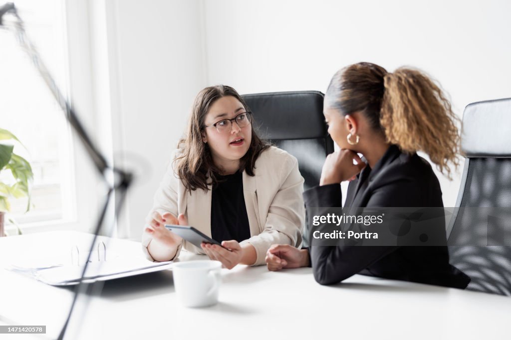 Business partners discussing over digital tablet in office