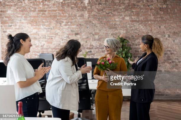 weibliche fachkräfte klatschen in die hände für eine geschäftsfrau, die eine blume im büro hält - man giving flowers stock-fotos und bilder