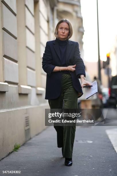 Guest wears a black turtleneck pullover, a black blazer jacket, khaki velvet large pants, black shiny leather block heels ankle shoes , gold...