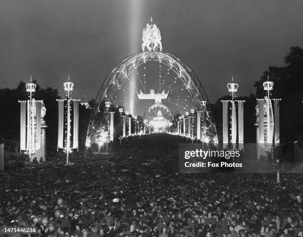 Crowd of people and beneath illuminations on The Mall during the celebrations that followed the Coronation of Elizabeth II, in Westminster, London,...