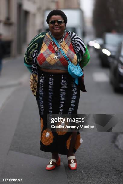 Gabriella Karefa-Johnson seen wearing a blue Balenciaga le Cagole bag, dark shades, a colourful patterned cardigan and cropped sweater, a knit skirt...