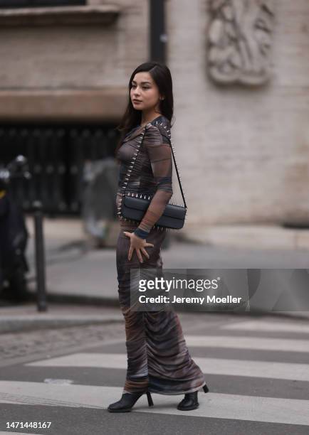 Diana Korkunova seen wearing a patterned long dress, high heels and a black bag before the Ester Manas show on March 04, 2023 in Paris, France.
