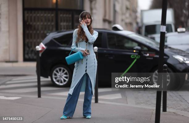 Fashion week guest seen wearing a blue dress with cutouts by Ester Manas, a blue bag by Ester Manas, wide jeans and matching blue high heels before...