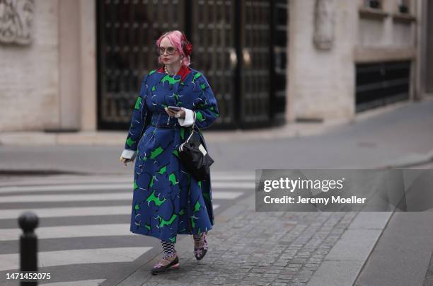 Fashion week guest seen wearing a blue and green flower patterned coat, ballet flats, a black bag, a rose hair clip and shades before the Ester Manas...