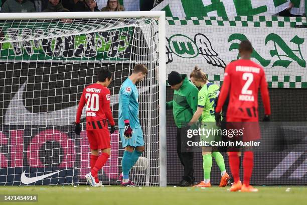 Players inspect a problem with the goal post during the Bundesliga match between VfL Wolfsburg and Eintracht Frankfurt at Volkswagen Arena on March...