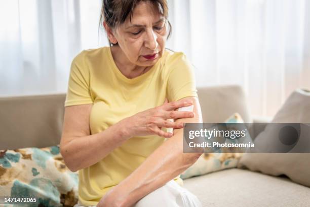 mature woman applies transdermal patch - transdermal stock pictures, royalty-free photos & images